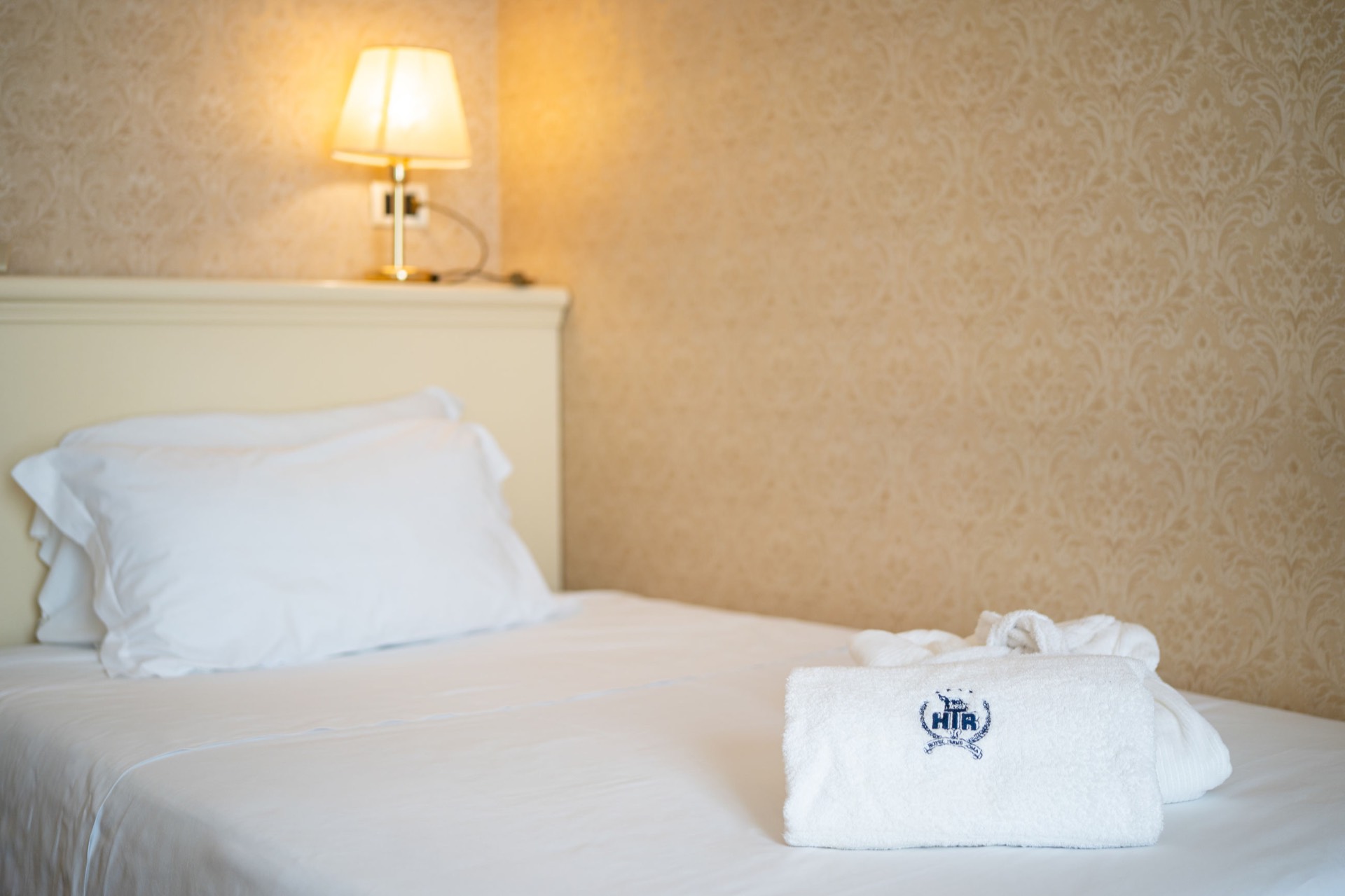 letto singolo con asciugamano e lampada