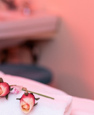 Due rose rosa su un asciugamano bianco, con uno sfondo sfocato in tonalità calde.