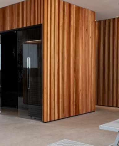 Modern interior with wooden slat walls and a glass door, featuring a minimalist design and neutral-colored flooring.